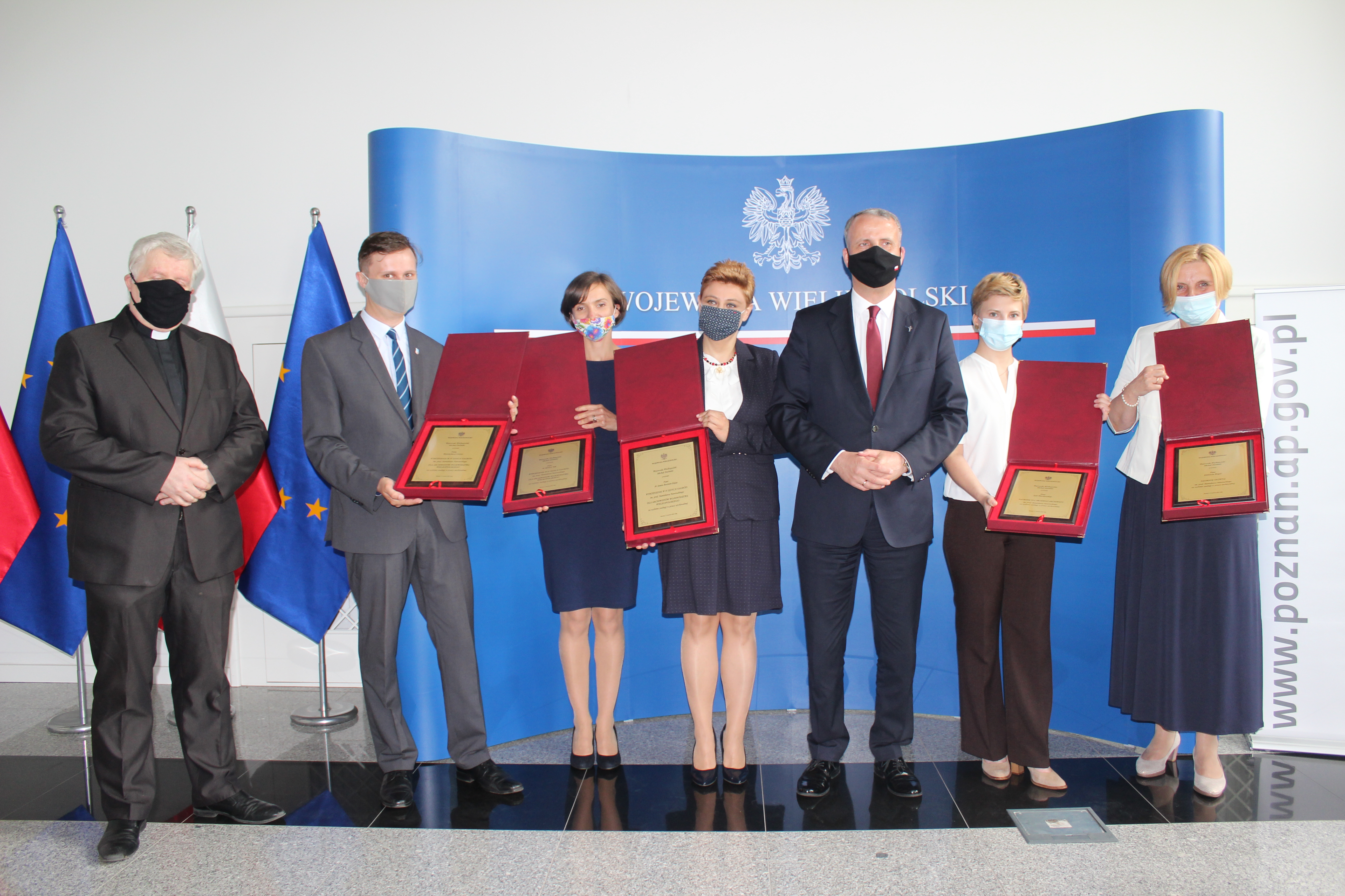 Nagrodzeni prezentują złote dyplomy w ozdobnych futerałach. 