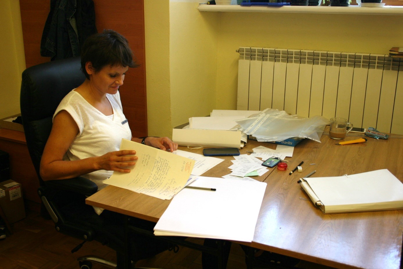 Kobieta siedzi przy biurku i przegląda dokumenty.