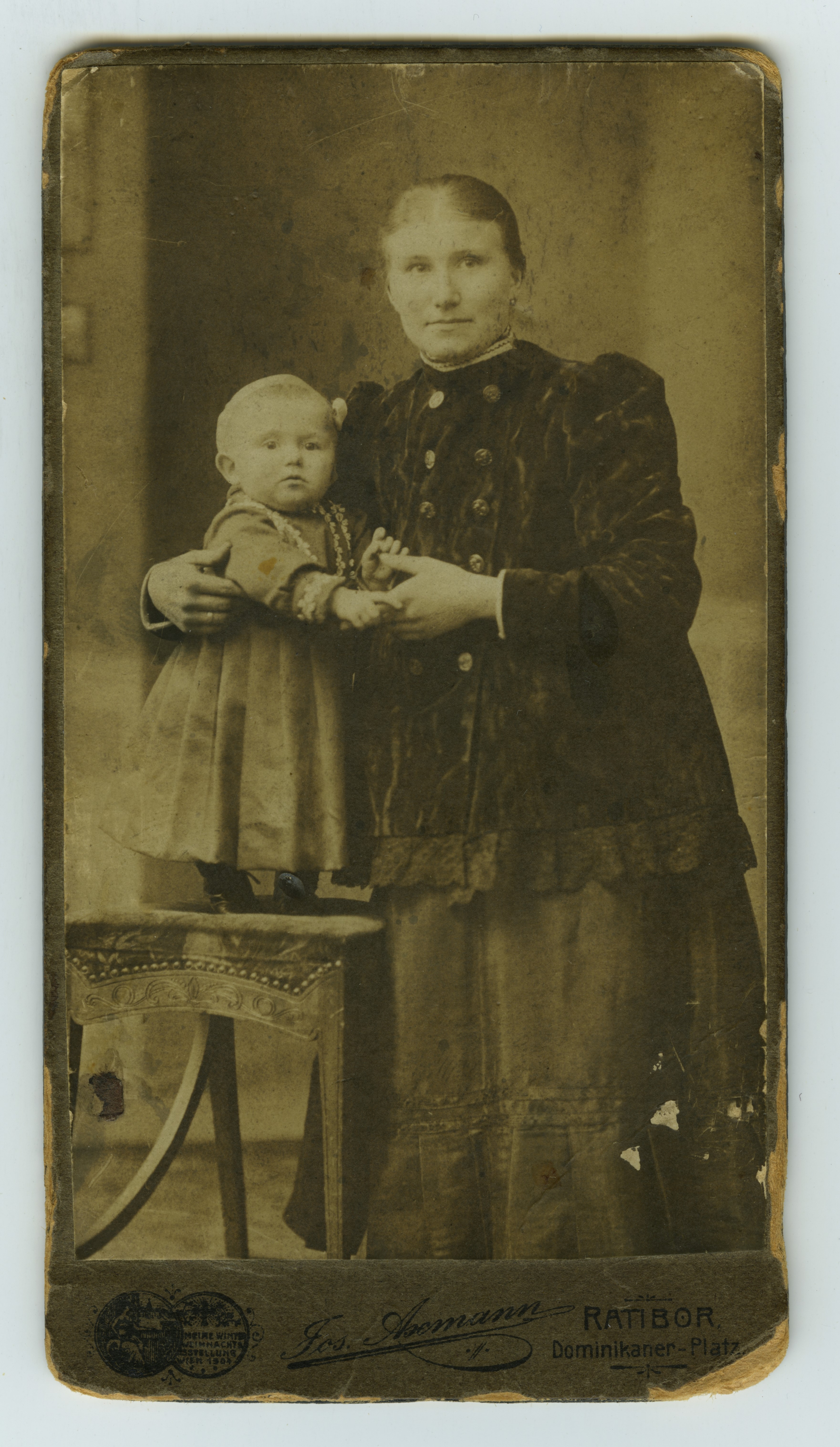 Kobieta obejmuje małe dziecko, dziecko stoi na stoliku. 