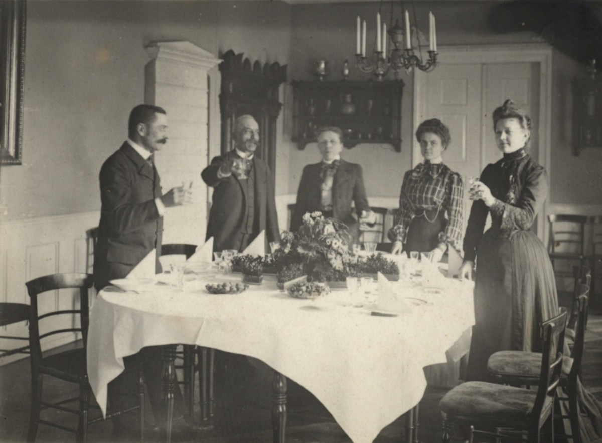 Dwóch mężczyzn i trzy kobiety stoją wokół stołu i wznoszą toast.
