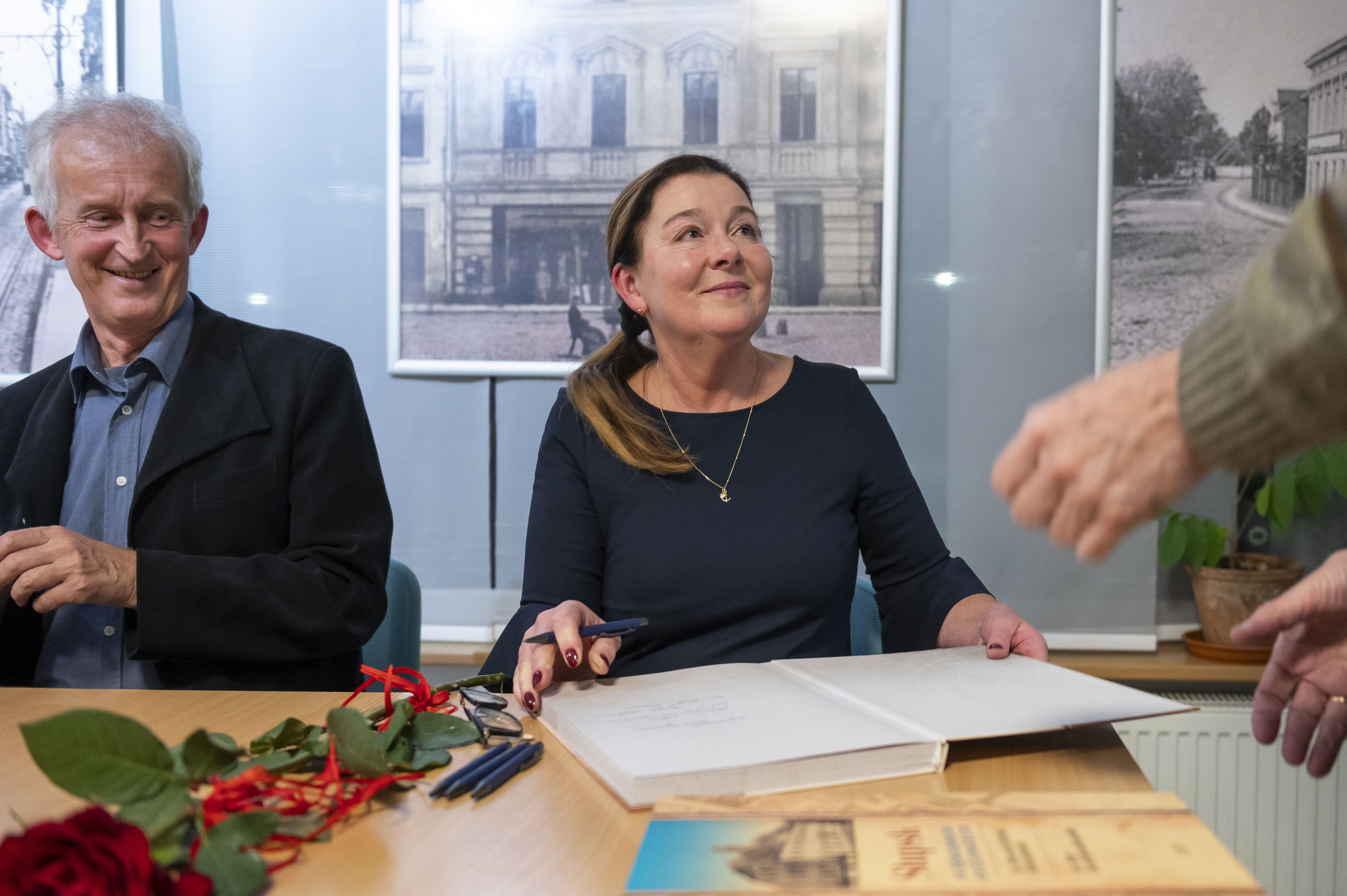 Krzysztof Urbanowicz i Dorota Cywińska siedzą przy stoliku i podpisują publikację.