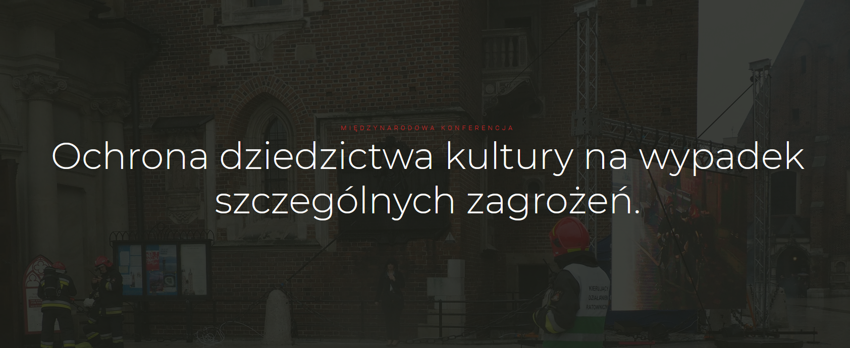 Baner z tekstem „Ochrona dziedzictwa kultury na wypadek szczególnych zagrożeń”. W tle zdjęcie strażaków przed budynkiem.